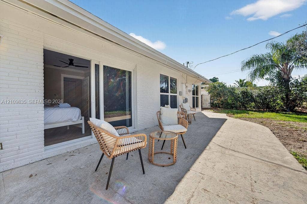 756 Cinnamon Road, North Palm Beach, North Palm Beach, FL 33408 Painted brick exterior featuring a concrete patio, sliding glass door, and lawn area