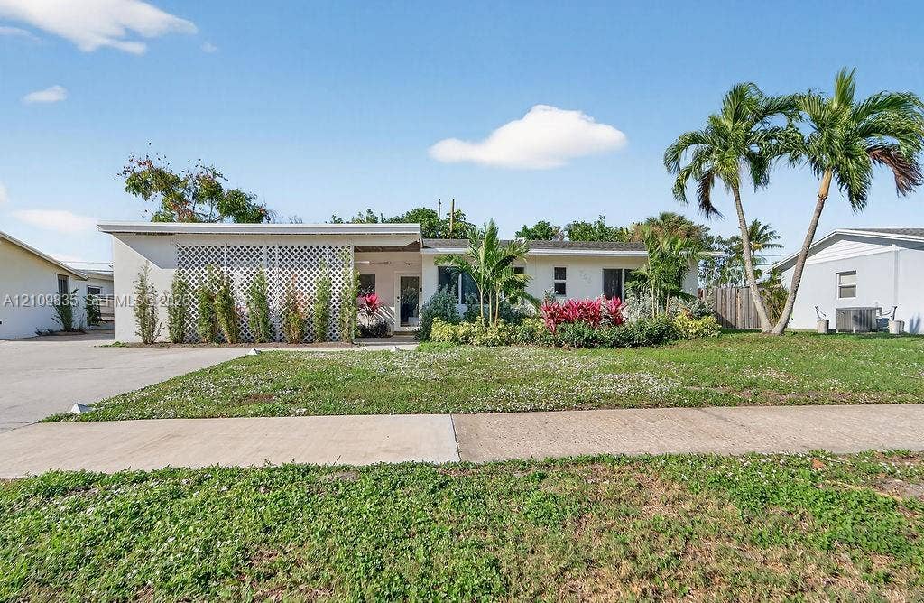 756 Cinnamon Road, North Palm Beach, North Palm Beach, FL 33408 Single-story residence featuring a flat roofline, decorative lattice screen, concrete driveway, and mature palm trees