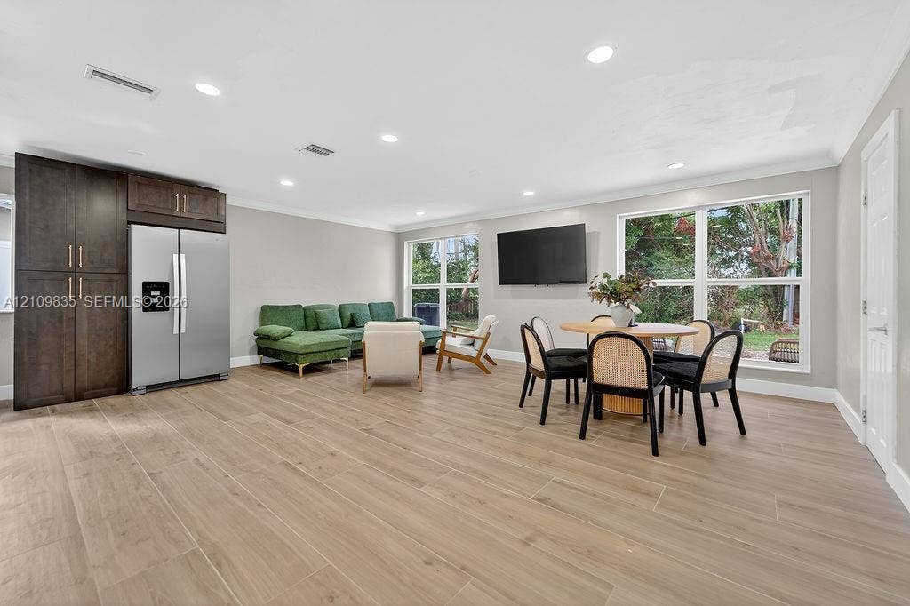756 Cinnamon Road, North Palm Beach, North Palm Beach, FL 33408 Open-concept living space featuring wood-finish tile flooring, recessed lighting, floor-to-ceiling dark wood cabinetry, and large windows