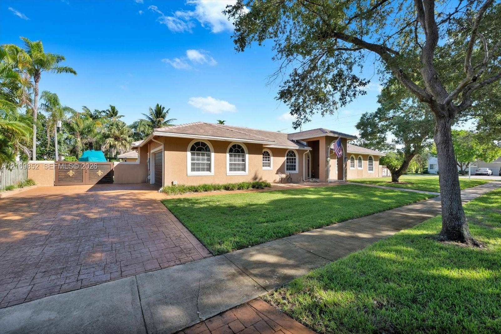 7901 SW 97th Street, Miami, FL 33156 Southern exposure, arched windows, a covered entryway, a patterned concrete driveway, and mature landscaping