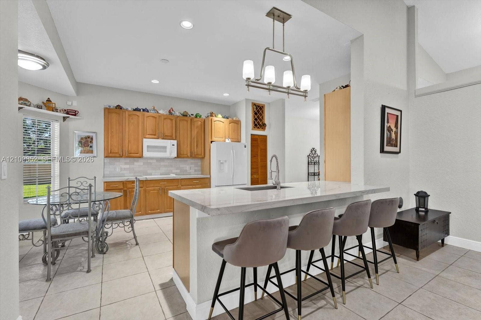 7901 SW 97th Street, Miami, FL 33156 Kitchen featuring solid wood cabinetry, quarzite countertops, subway tiled backsplash, newer appliances , with the breakfast area off to the left *