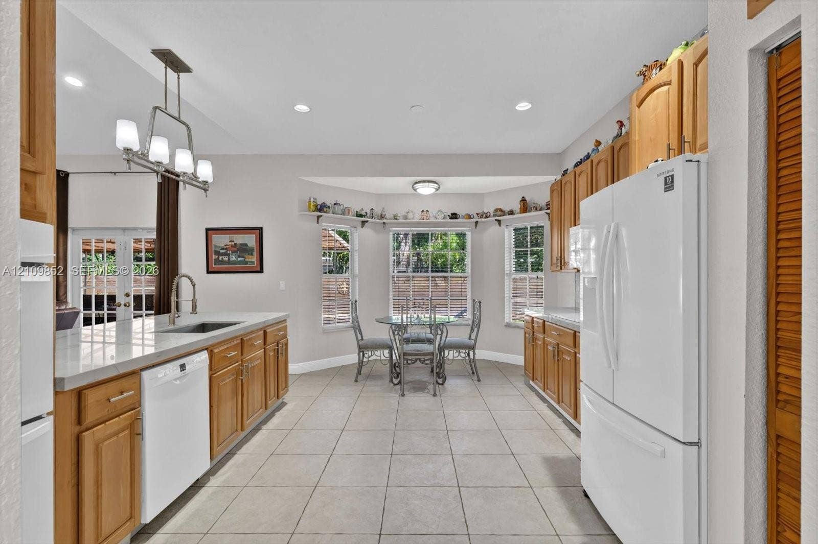 7901 SW 97th Street, Miami, FL 33156 Kitchen featuring light-finish cabinetry, neutral tile flooring, beautiful quartzite countertops and a charming breakfast nook with lots of windows *