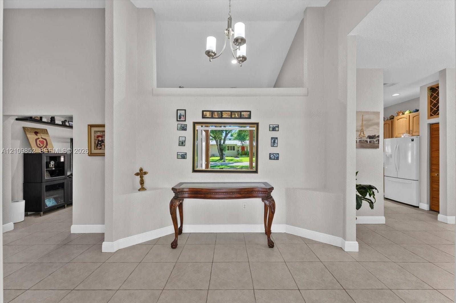 7901 SW 97th Street, Miami, FL 33156 Entryway featuring volume ceilings, neutral ceramic tile flooring, a multi-arm chandelier, and a recessed wall niche *
