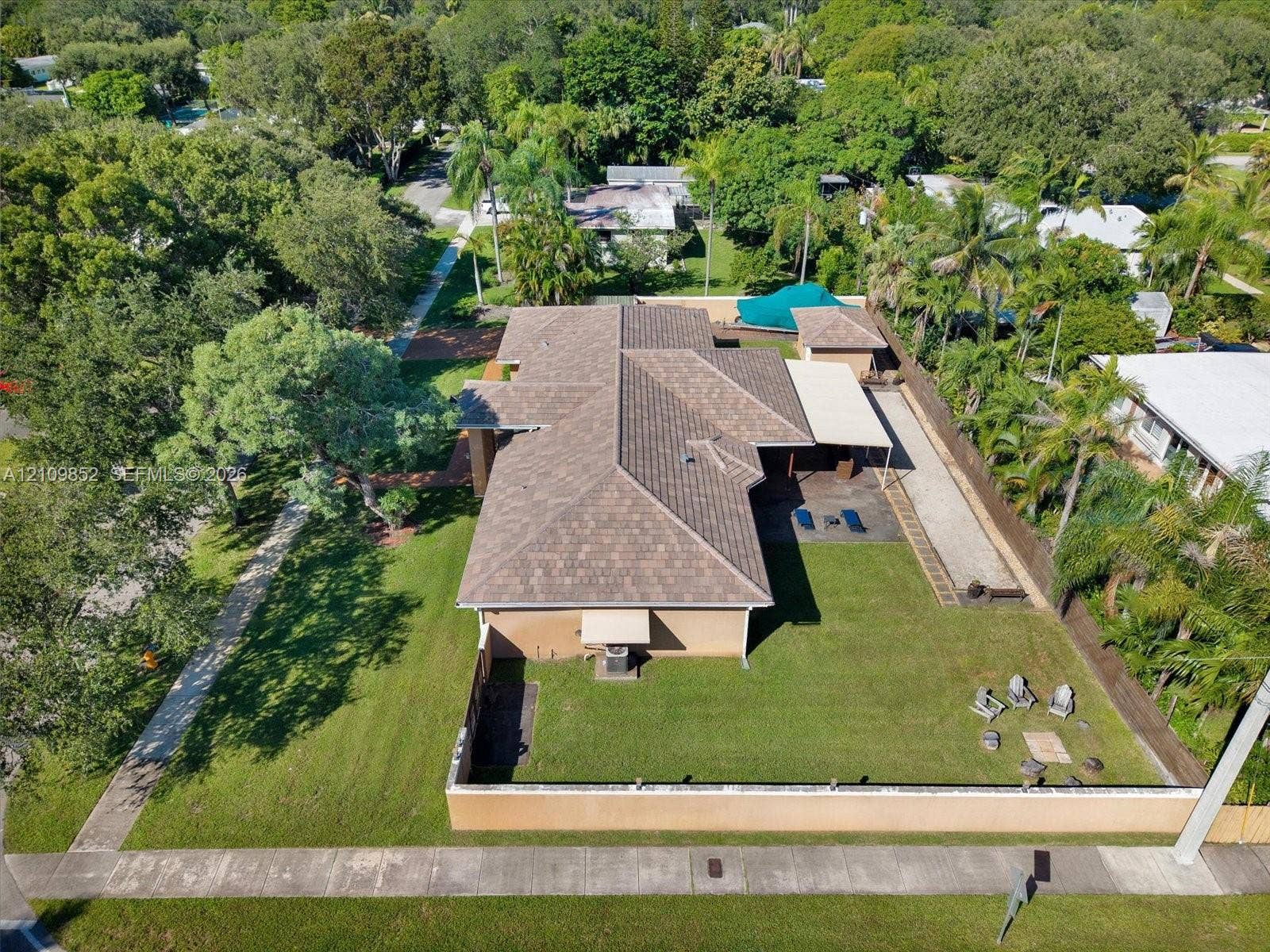 7901 SW 97th Street, Miami, FL 33156 Aerial perspective of the home featuring a brand new 2026 concrete flat tiled roof, manicured lawn, concrete perimeter wall with lights and a covered patio *