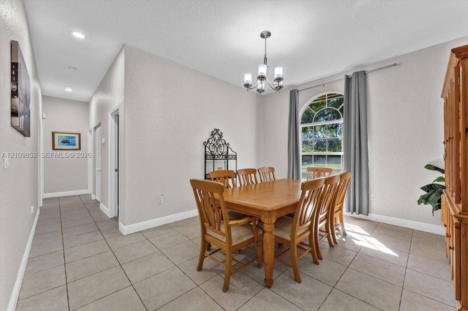 7901 SW 97th Street, Miami, FL 33156 Neutral-toned interior featuring ceramic tile flooring, an arched window with decorative muntins, and a multi-arm chandelier