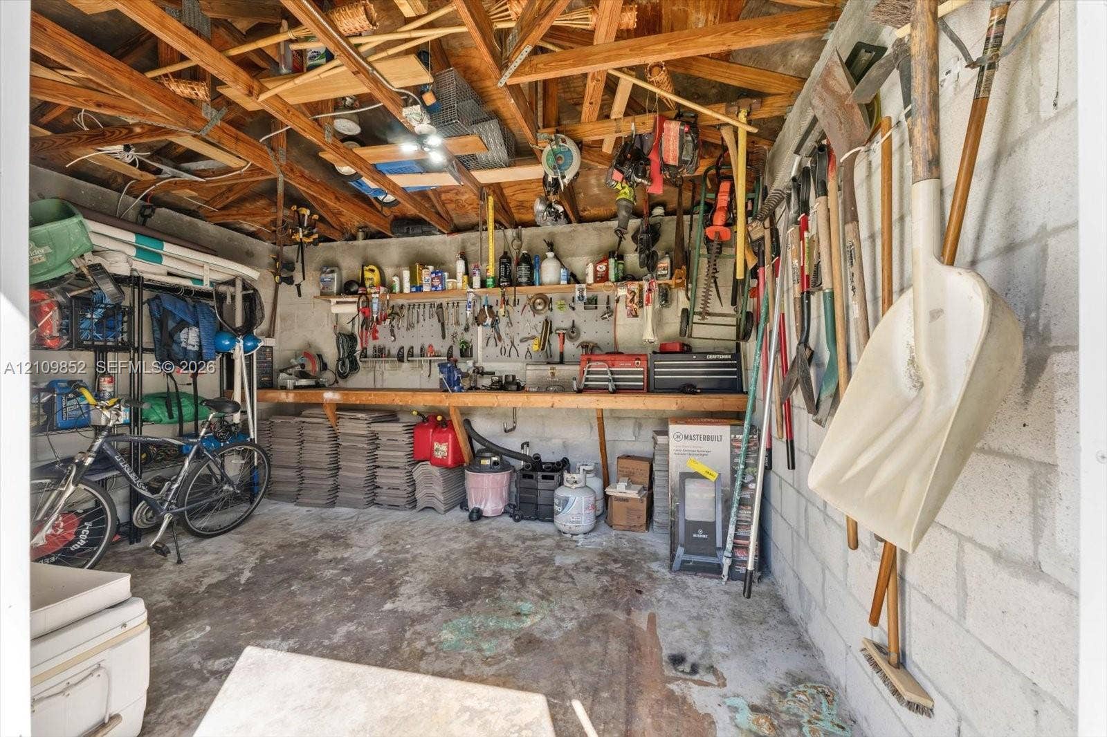7901 SW 97th Street, Miami, FL 33156 CBS shed with brand new tiled roof, equipped with electricity, exposed wood truss ceiling, and a built-in wooden workbench *