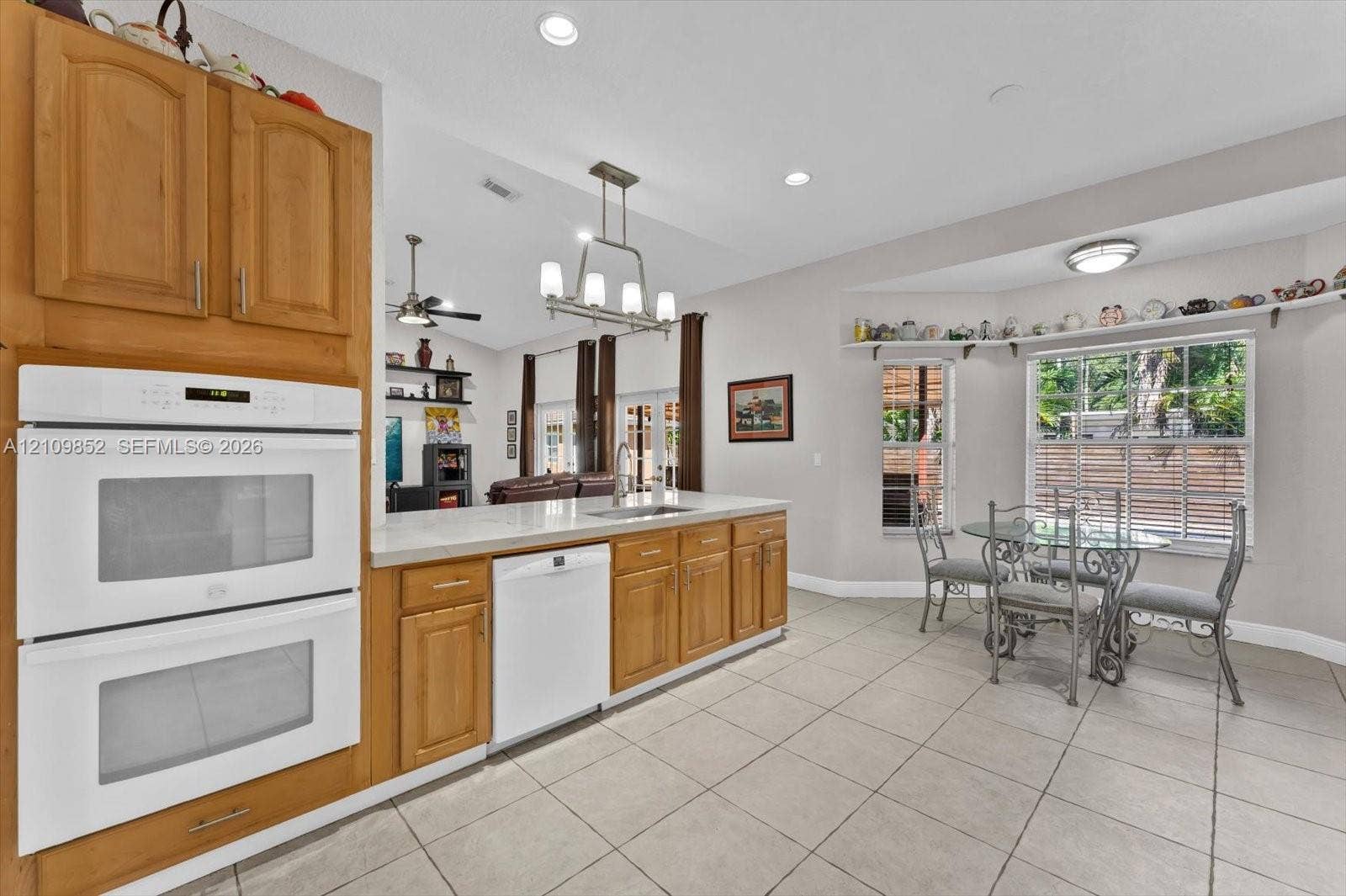 7901 SW 97th Street, Miami, FL 33156 Kitchen featuring wooden cabinetry, white double wall oven, Bosch dishwasher, tile flooring, and a recessed window breakfast nook *