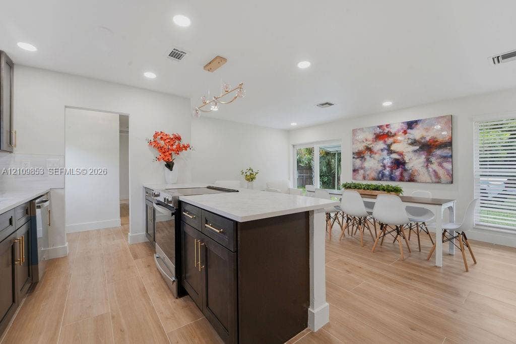 800 Alamanda Drive, North Palm Beach, North Palm Beach, FL 33408 Kitchen featuring dark wood cabinetry, a central island with a stone-finish countertop, recessed lighting, wood-finish flooring, and a modern tiered chandelier