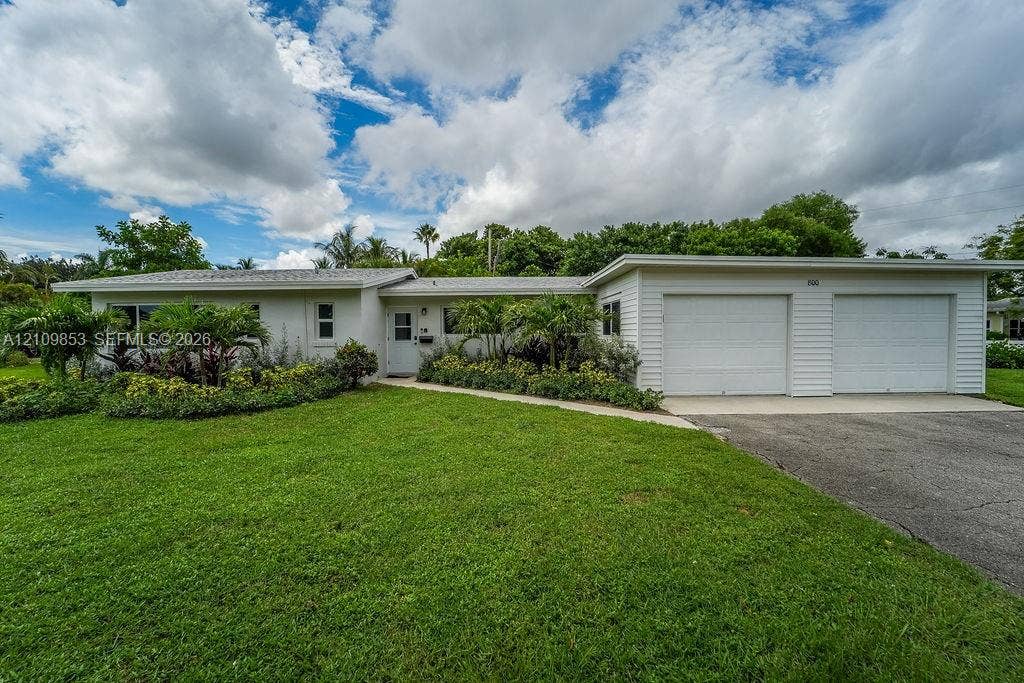 800 Alamanda Drive, North Palm Beach, North Palm Beach, FL 33408 Single-story exterior featuring white horizontal siding, a two-car garage, an asphalt driveway, and manicured landscaping