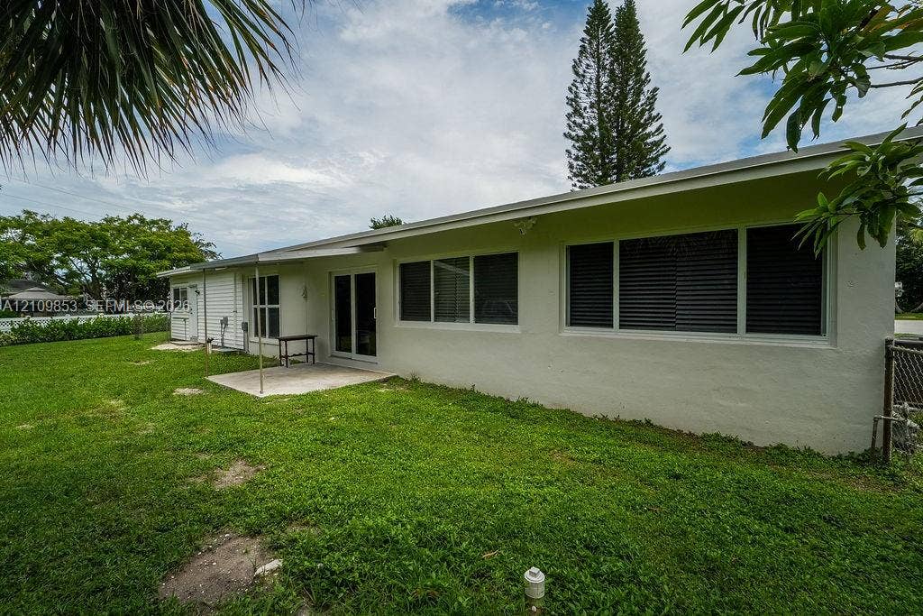 800 Alamanda Drive, North Palm Beach, North Palm Beach, FL 33408 Exterior rear facade featuring a concrete patio, sliding glass doors, white siding, and horizontal windows