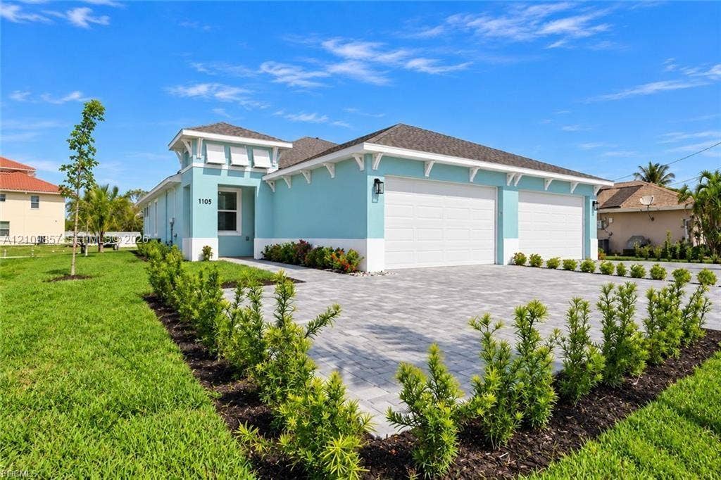 1105 SE 38th Street, Cape Coral, FL 33904 Single-story exterior featuring a paver driveway, three-car garage, decorative corbels, and professional landscaping