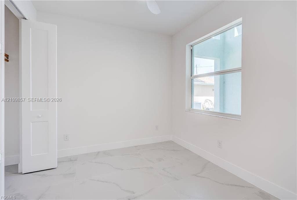 1105 SE 38th Street, Cape Coral, FL 33904 Room featuring large-format tile flooring, bright neutral walls, a single-hung window, and a built-in closet with double-panel doors
