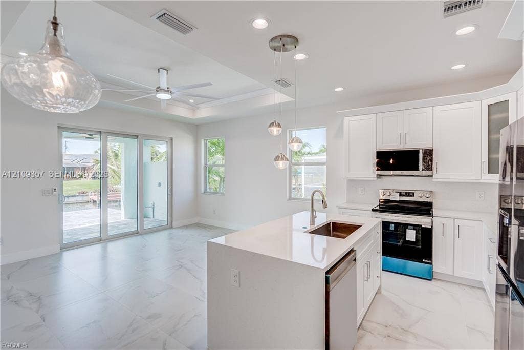 1105 SE 38th Street, Cape Coral, FL 33904 Kitchen featuring white shaker-style cabinetry, quartz countertops, a central island with a stainless steel undermount sink, recessed lighting, and large-format tile flooring