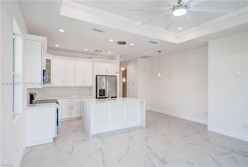 1105 SE 38th Street, Cape Coral, FL 33904 Kitchen featuring white cabinetry, center island with stone-finish countertop, recessed lighting, tray ceiling, and large-format tile flooring