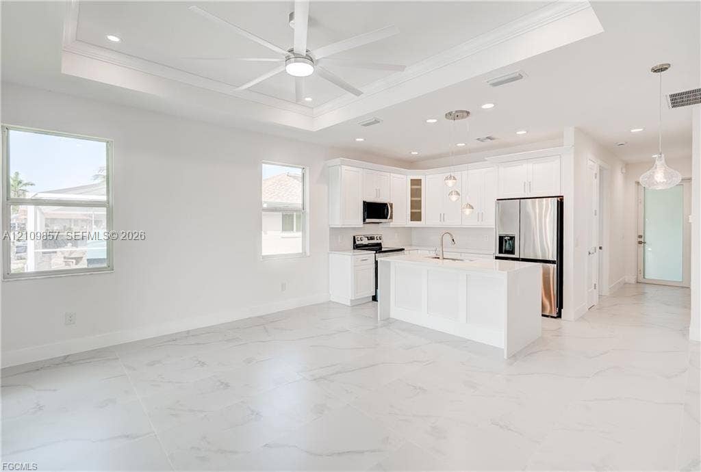 1105 SE 38th Street, Cape Coral, FL 33904 Kitchen featuring white cabinetry, an island with stone-finish countertops, recessed lighting, a tray ceiling with a center fan, and polished tile flooring