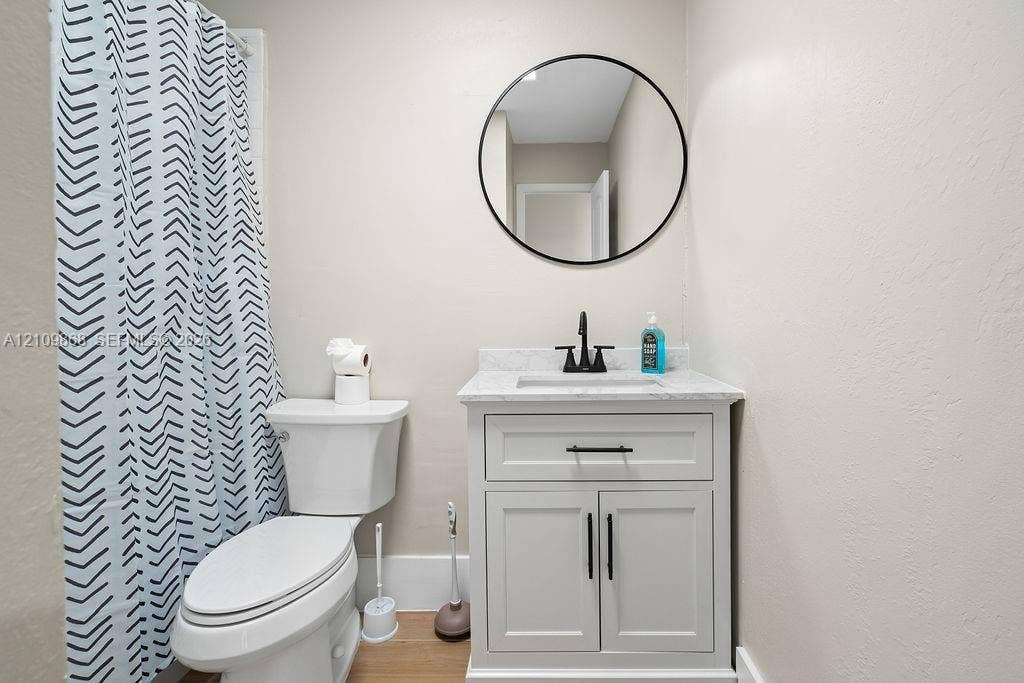 736 Prosperity Farms Road, North Palm Beach, North Palm Beach, FL 33408 White shaker-style vanity with a stone-composite countertop, integrated sink, matte black faucet, and circular wall-mounted mirror