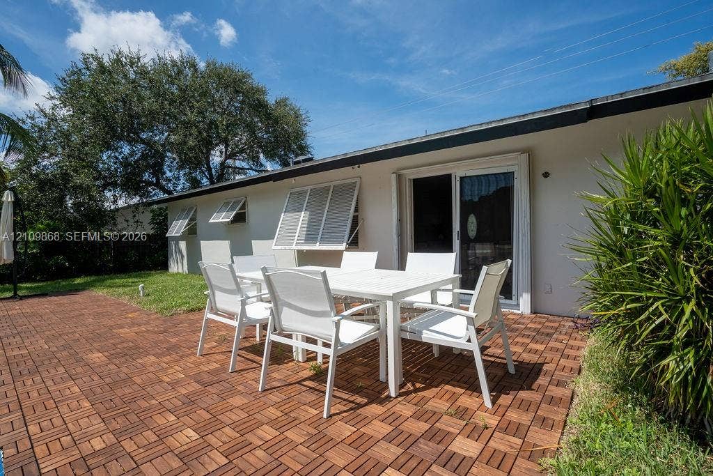 736 Prosperity Farms Road, North Palm Beach, North Palm Beach, FL 33408 Exterior patio featuring patterned modular wood decking, sliding glass doors, and louvered storm shutters