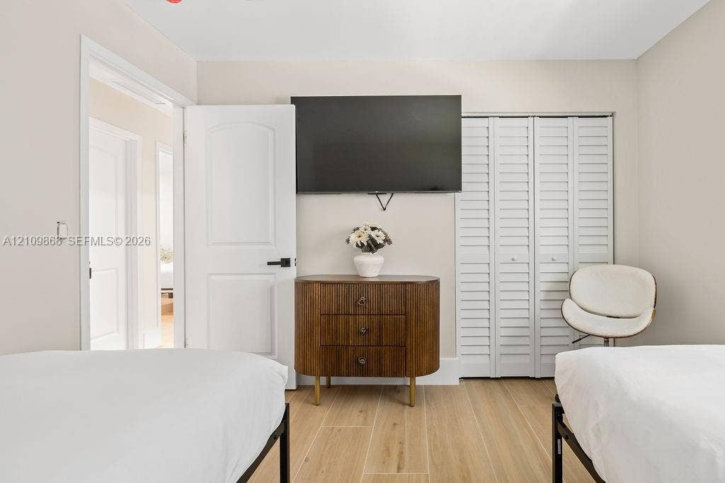 736 Prosperity Farms Road, North Palm Beach, North Palm Beach, FL 33408 Neutral-toned interior featuring wood-finish flooring, white louvered closet doors, and a solid-core interior door with matte black hardware