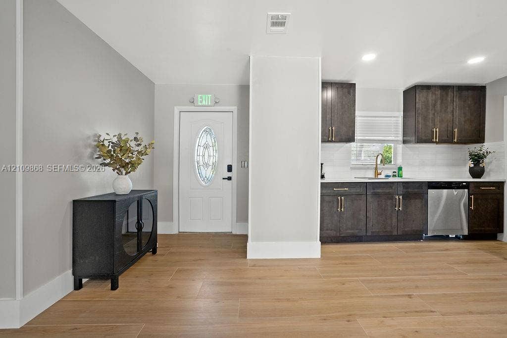 736 Prosperity Farms Road, North Palm Beach, North Palm Beach, FL 33408 Wood-finish flooring, dark cabinetry with gold-tone hardware, stainless steel dishwasher, recessed lighting, and white door with oval decorative glass insert