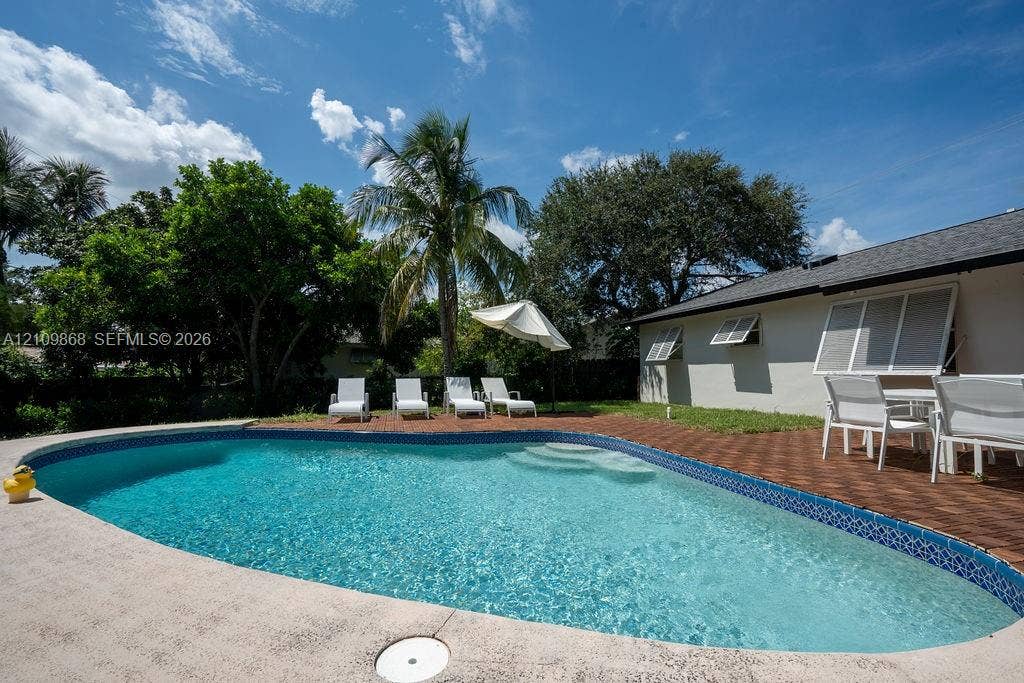736 Prosperity Farms Road, North Palm Beach, North Palm Beach, FL 33408 In-ground swimming pool featuring tile coping and integrated steps, surrounded by a paved brick patio and concrete decking