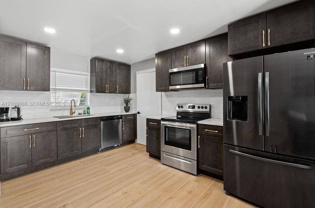 736 Prosperity Farms Road, North Palm Beach, North Palm Beach, FL 33408 Kitchen featuring dark wood-finish cabinetry, quartz countertops, stainless steel appliances, and wood-finish tile flooring
