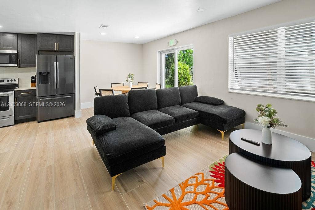 736 Prosperity Farms Road, North Palm Beach, North Palm Beach, FL 33408 Open-concept living space featuring wood-finish flooring, dark cabinetry, recessed lighting, and a sliding glass door