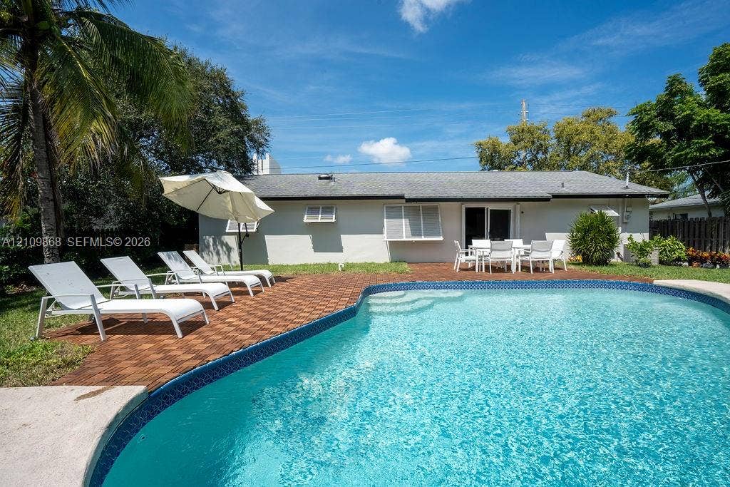736 Prosperity Farms Road, North Palm Beach, North Palm Beach, FL 33408 Backyard featuring a swimming pool, brick-paver decking, perimeter fencing, and mature landscaping