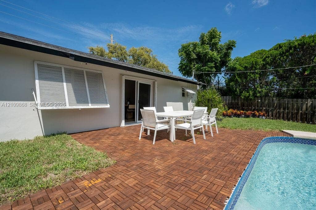 736 Prosperity Farms Road, North Palm Beach, North Palm Beach, FL 33408 Backyard featuring a swimming pool, wood-finish deck tiling, a manicured lawn, and horizontal exterior window shutters