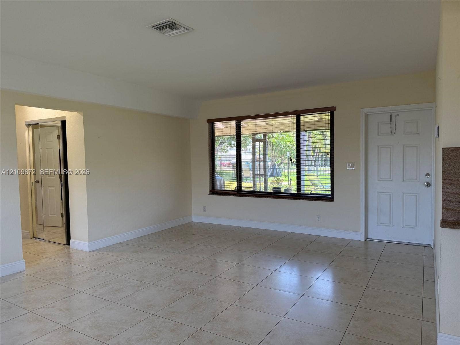 811 NE 10th Street, #5, Hallandale Beach, Hallandale Beach, FL 33009 Neutral-toned ceramic tile flooring, expansive window with dark trim, multi-panel exterior entry door, and a built-in mirrored closet door