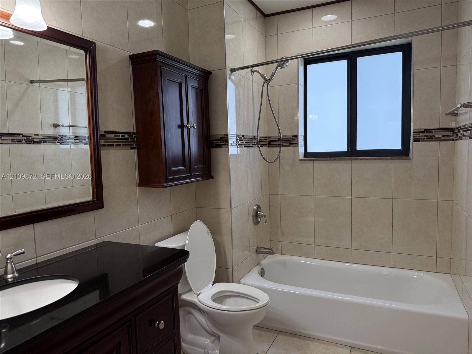 811 NE 10th Street, #5, Hallandale Beach, Hallandale Beach, FL 33009 Bathroom featuring large-format wall tiling with a mosaic accent strip, dark wood-finish vanity with a stone countertop, built-in wall cabinetry, and a bathtub with a handheld shower fixture