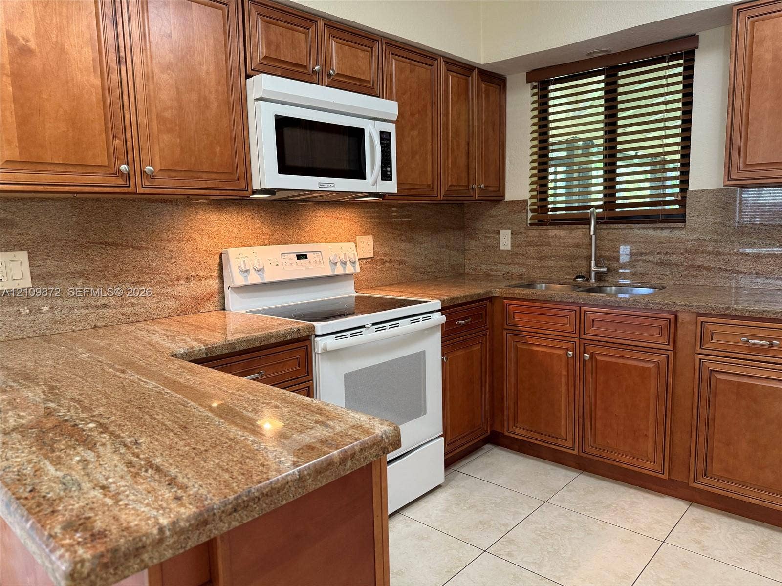 811 NE 10th Street, #5, Hallandale Beach, Hallandale Beach, FL 33009 Kitchen featuring wood cabinetry, stone countertops with integrated backsplash, white electric range with over-the-range microwave, and tile flooring