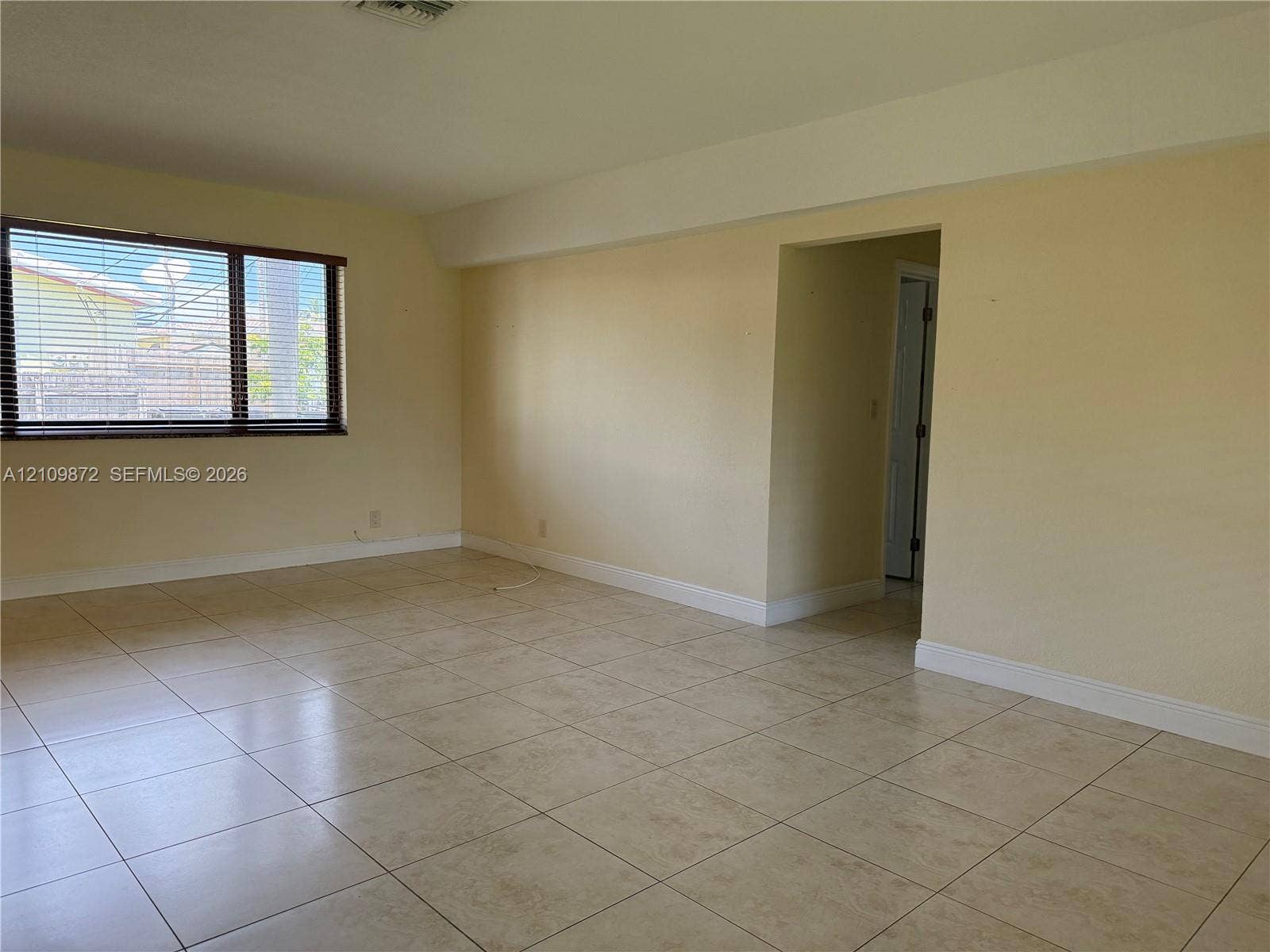 811 NE 10th Street, #5, Hallandale Beach, Hallandale Beach, FL 33009 Interior space featuring large-format ceramic tile flooring, neutral wall tones, and a window with horizontal blinds