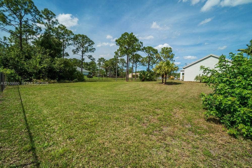 8231 Coconut Boulevard, West Palm Beach, West Palm Beach, FL 33412 Expansive rear grounds featuring manicured grass, mature perimeter pine trees, native shrubbery, and chain-link fencing