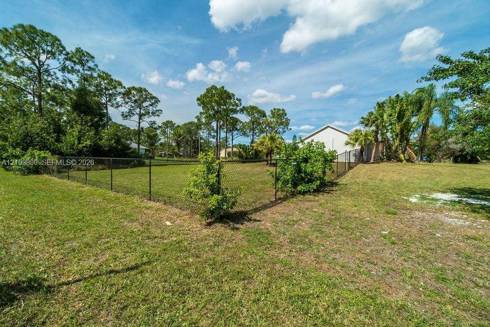 8231 Coconut Boulevard, West Palm Beach, West Palm Beach, FL 33412 Fenced yard featuring a level lawn, mature shade trees, and perimeter landscaping