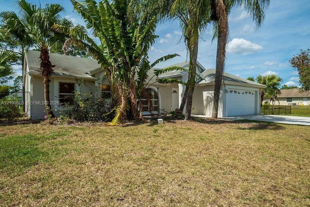 8231 Coconut Boulevard, West Palm Beach, West Palm Beach, FL 33412 Single-story residence featuring a light-toned stucco exterior, a decorative arched entryway, and an attached two-car garage