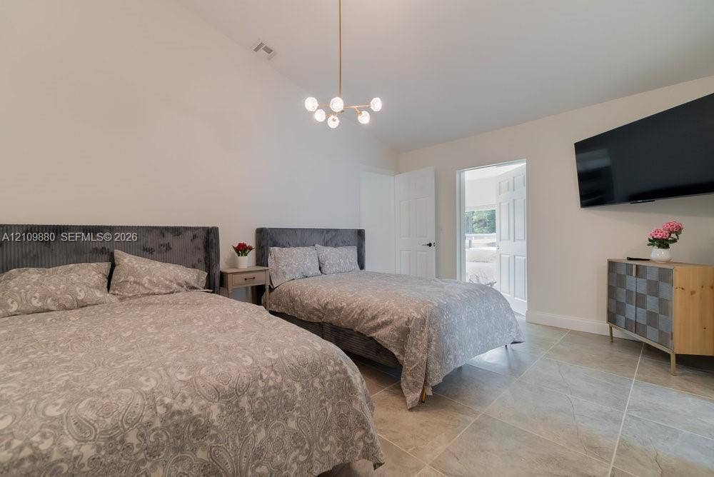 8231 Coconut Boulevard, West Palm Beach, West Palm Beach, FL 33412 Vaulted ceiling featuring a modern multi-globe chandelier and large-format tile flooring