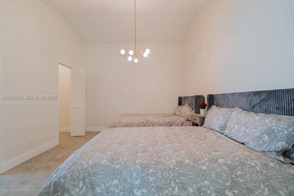 8231 Coconut Boulevard, West Palm Beach, West Palm Beach, FL 33412 High-ceiling interior space featuring tile flooring, a brass-finish multi-arm chandelier, and a louvered-door closet