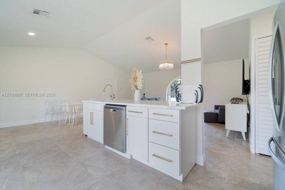 8231 Coconut Boulevard, West Palm Beach, West Palm Beach, FL 33412 Kitchen island featuring white shaker-style cabinetry, quartz countertops, a brass faucet, and a stainless steel dishwasher, complemented by tile flooring
