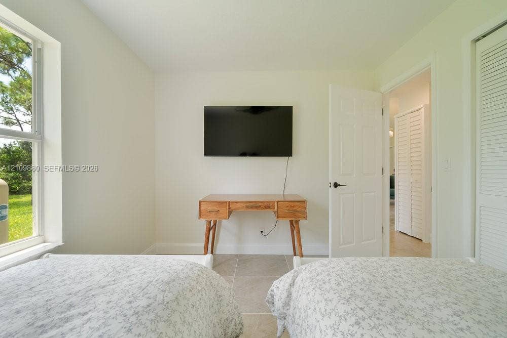 8231 Coconut Boulevard, West Palm Beach, West Palm Beach, FL 33412 Neutral-toned interior featuring large windows, neutral floor tile, and white louvered closet doors