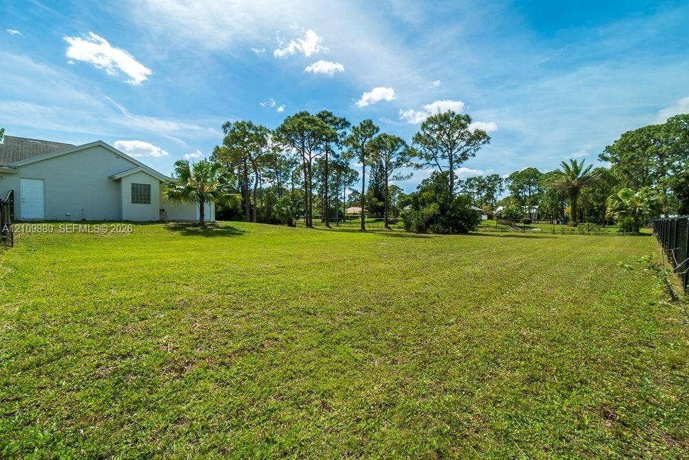 8231 Coconut Boulevard, West Palm Beach, West Palm Beach, FL 33412 Expansive backyard featuring an open grass lawn, mature trees, and perimeter fencing