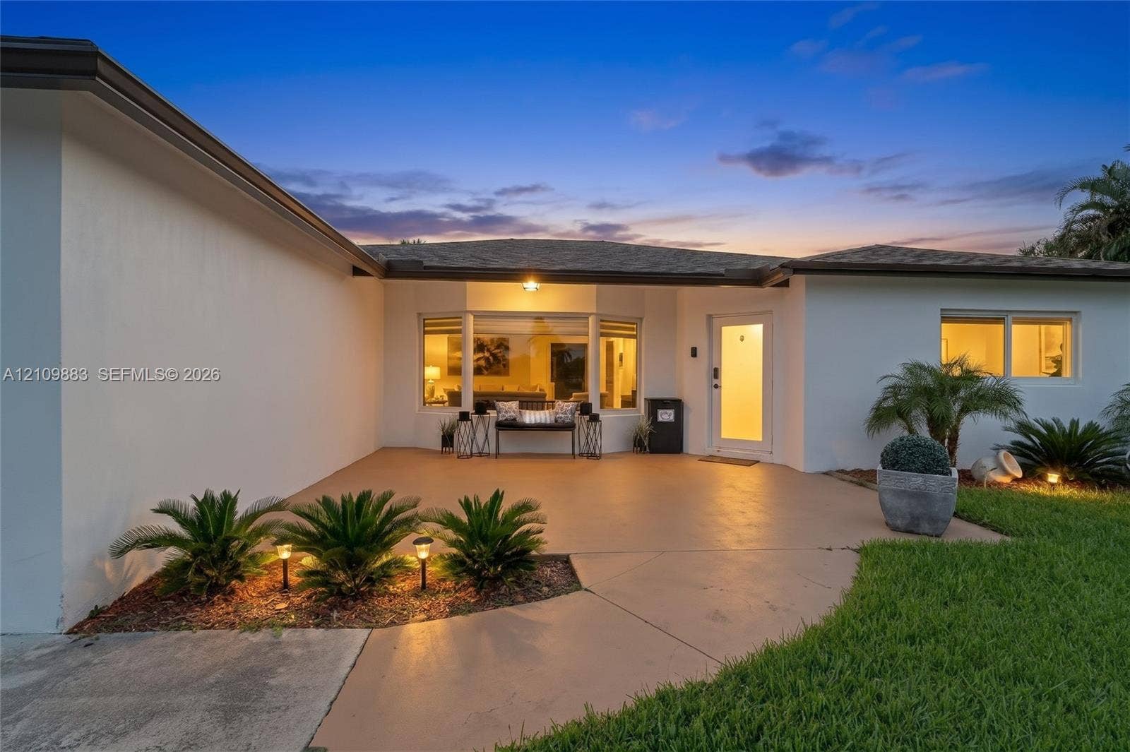 751 SW 54th Avenue, Margate, FL 33068 Single-story exterior featuring a smooth stucco finish, a covered concrete patio, a large bay window, and manicured landscaping