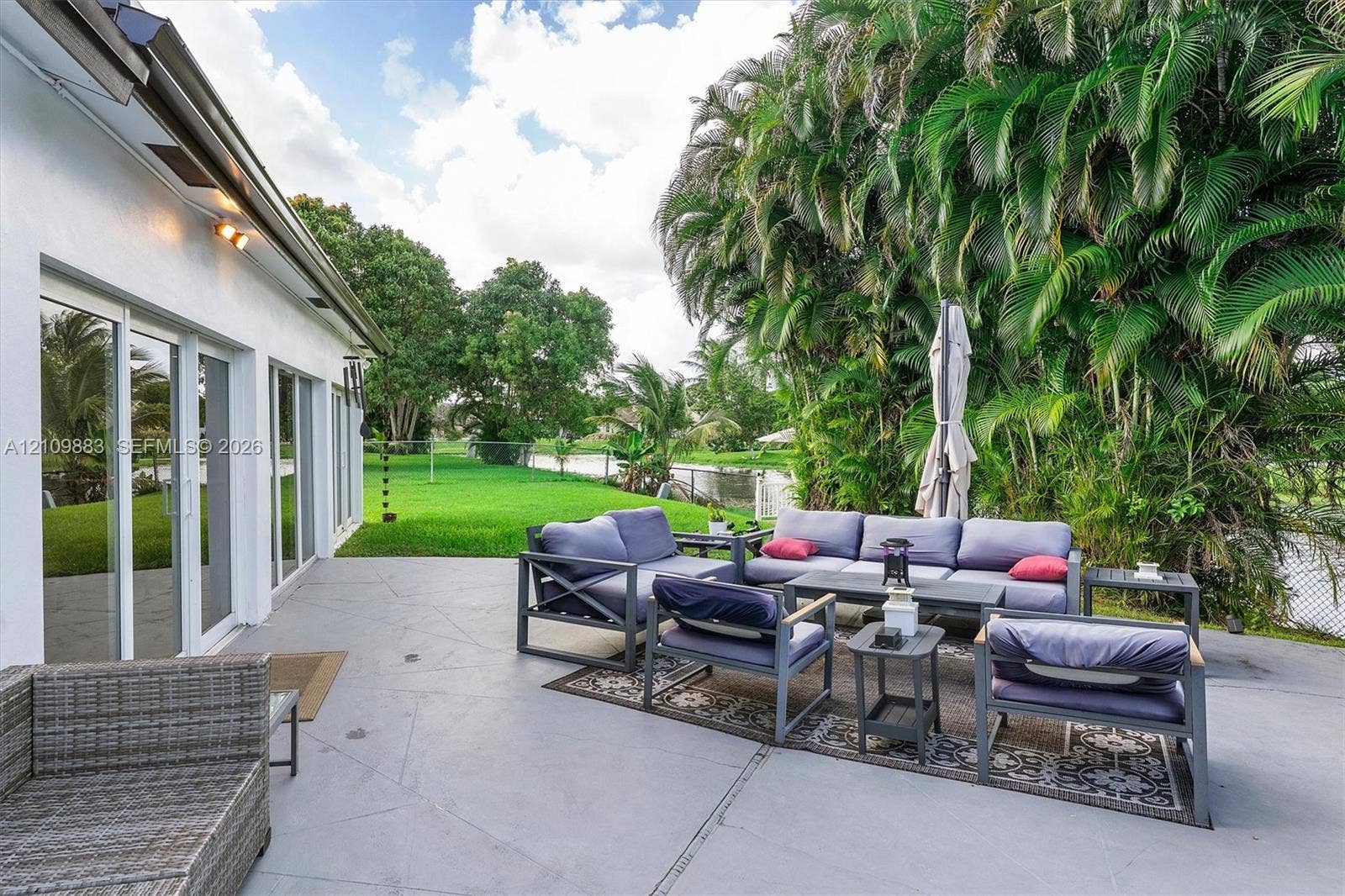 751 SW 54th Avenue, Margate, FL 33068 Concrete patio featuring sliding glass doors and expansive backyard greenery