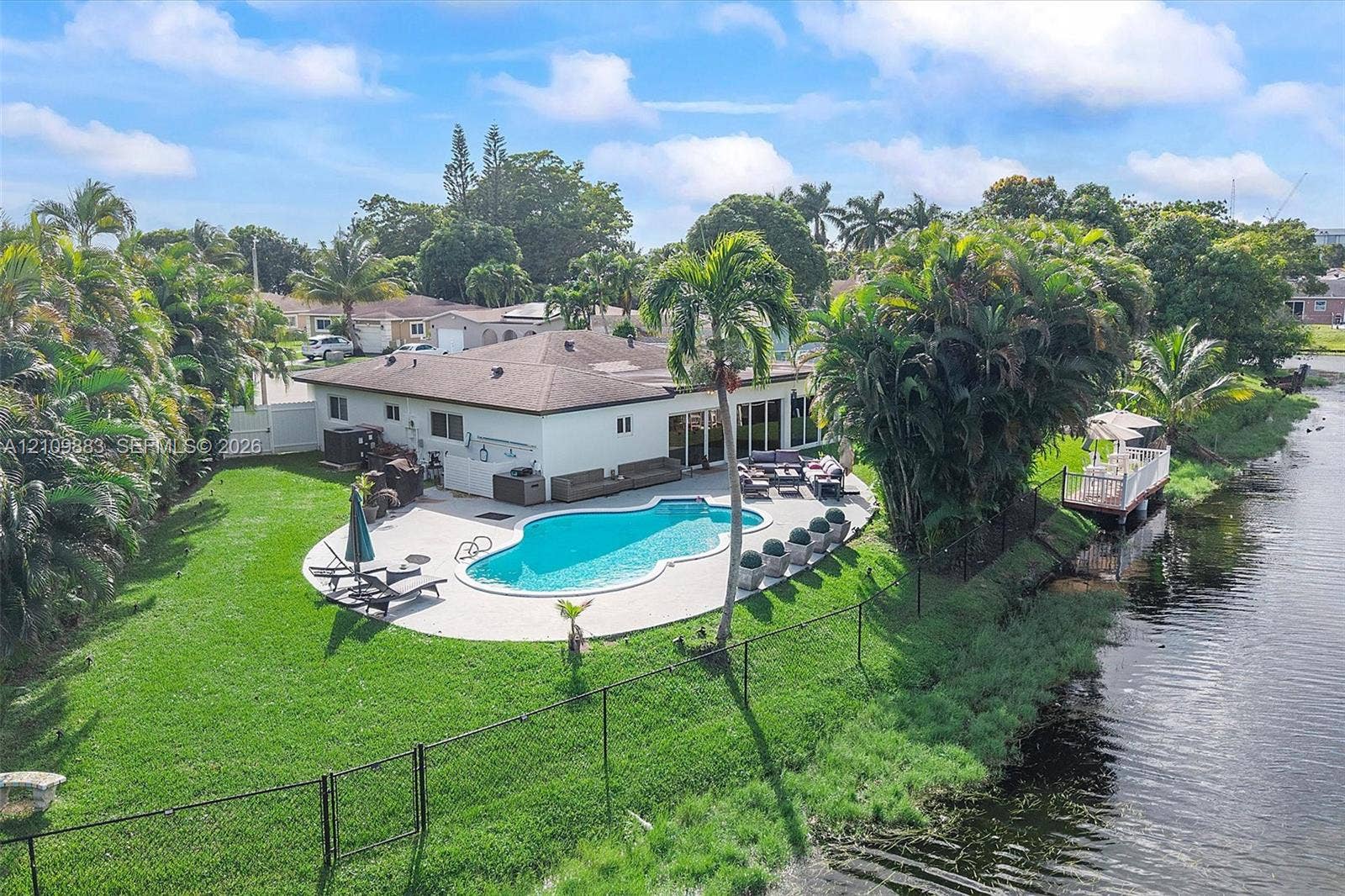 751 SW 54th Avenue, Margate, FL 33068 Waterfront property featuring a private swimming pool, expansive concrete patio, manicured lawn, and dedicated private dock