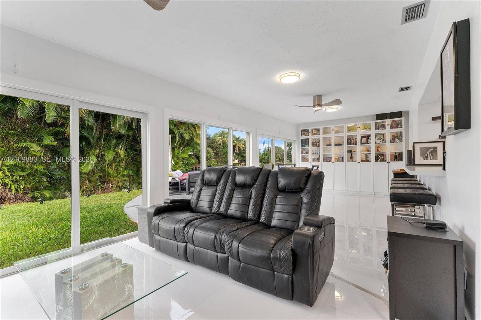 751 SW 54th Avenue, Margate, FL 33068 Open-concept living space featuring high-gloss tile flooring, floor-to-ceiling sliding glass doors, built-in white cabinetry, and recessed ceiling lighting
