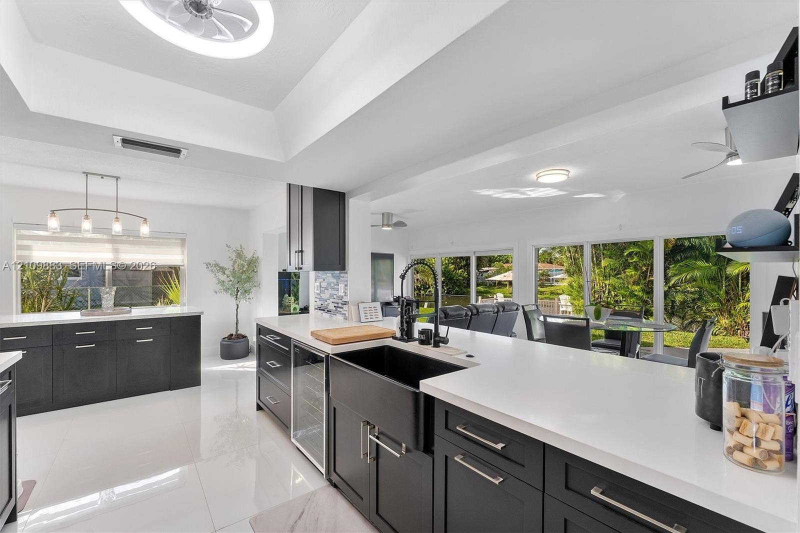 751 SW 54th Avenue, Margate, FL 33068 Kitchen featuring dark cabinetry, expansive quartz countertops, a matte black farmhouse sink with a coordinating high-arch faucet, and a built-in wine cooler