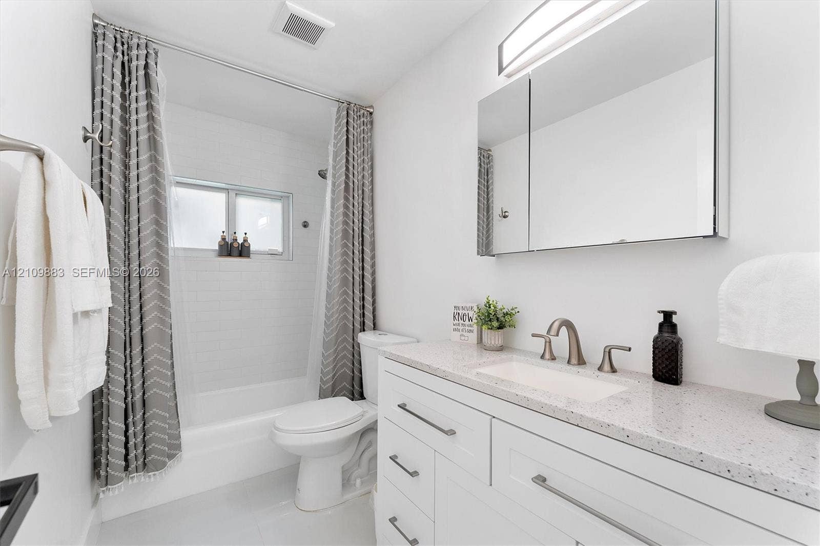751 SW 54th Avenue, Margate, FL 33068 Bathroom featuring a vanity with a light-toned speckled countertop, an undermount sink, brushed nickel faucet hardware, a mirrored medicine cabinet, and a tiled tub-shower surround