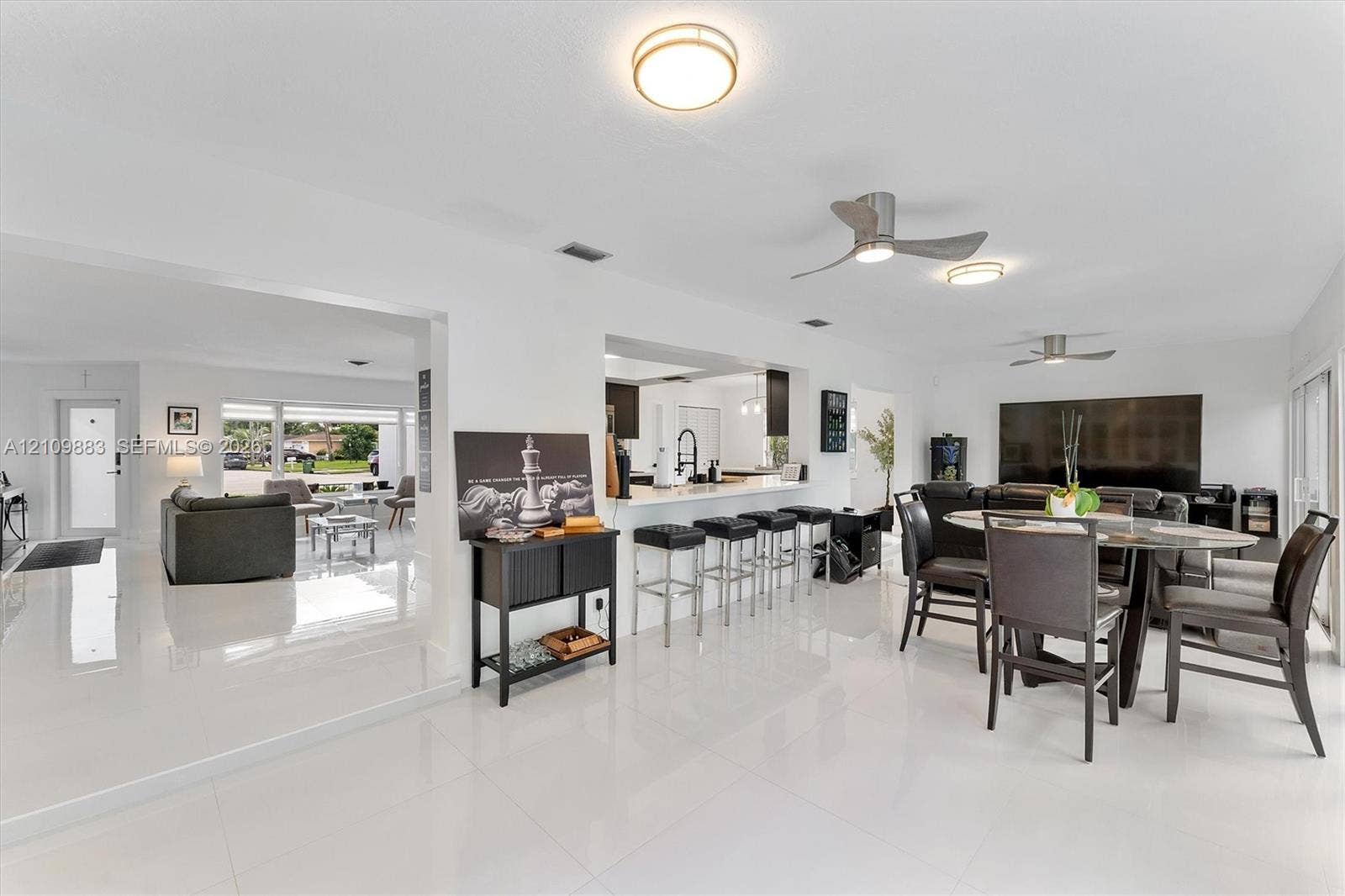 751 SW 54th Avenue, Margate, FL 33068 Open concept interior featuring polished tile flooring, recessed lighting, ceiling fans, and a kitchen peninsula with bar seating