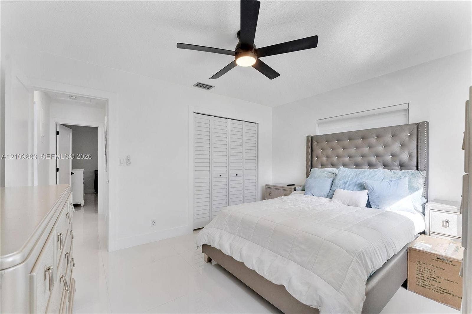 751 SW 54th Avenue, Margate, FL 33068 Bedroom featuring white tile flooring, white louvered closet doors, and a five-blade ceiling fan with integrated lighting