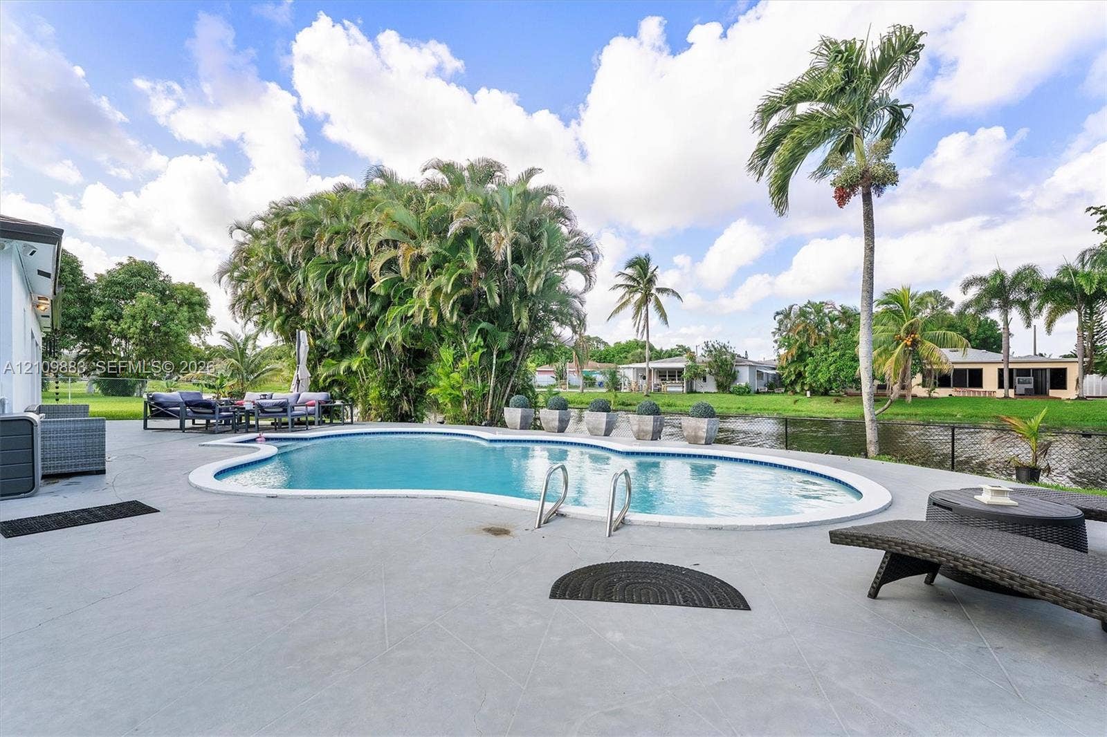 751 SW 54th Avenue, Margate, FL 33068 Freeform swimming pool with a concrete pool deck, mature landscaping, and water frontage