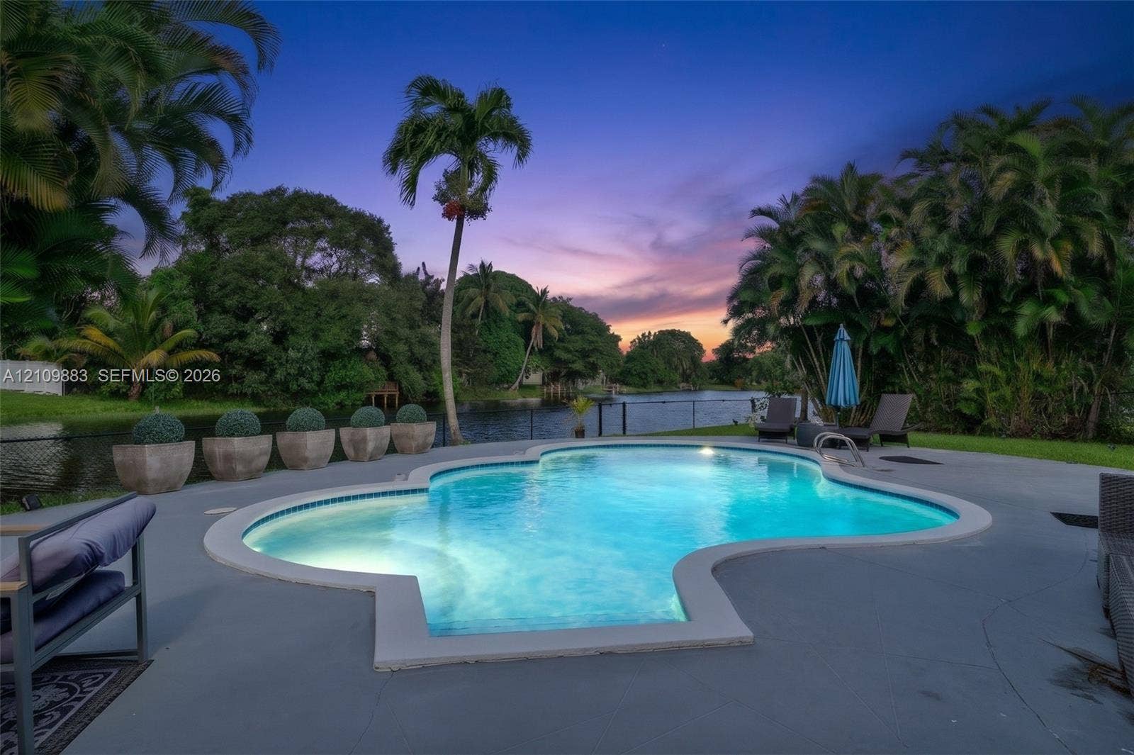 751 SW 54th Avenue, Margate, FL 33068 Freeform swimming pool with a concrete pool deck, water frontage, and mature palm trees